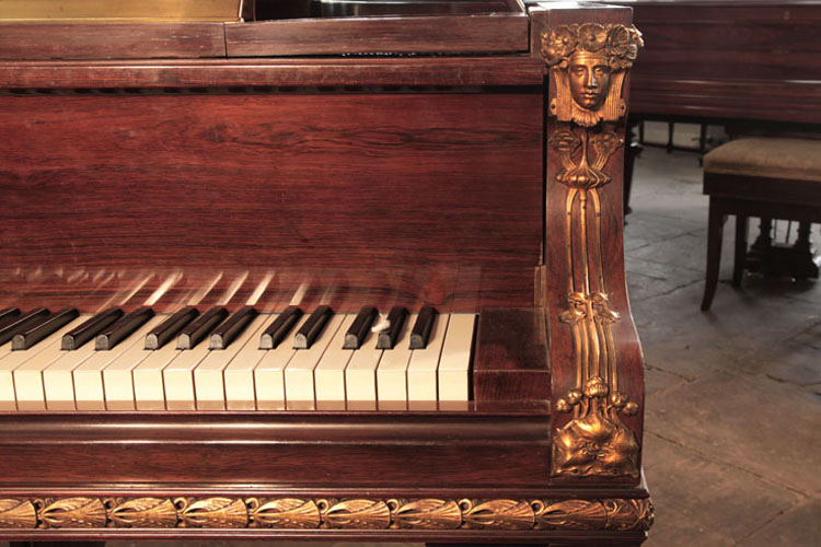 Symmetrical female heads with flowing tresses and floral headbands in gilted metal sit atop each cheek with flowing tendrils leading to stylised foliage.