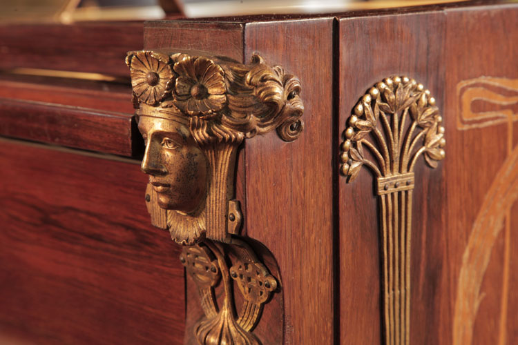 Symmetrical female heads with flowing tresses and floral headbands in gilted metal sit atop each cheek