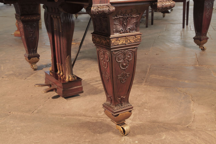 The three piano legs are heavily carved, yet appear understated due to minimal use of gilted filigree banding. Each leg is a tapered, four-sided baluster shape, carved with sunflowers and foliage.