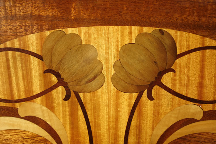 Detail of symmetrical inlay of flowers and stems in a variety of woods on a satinwood background