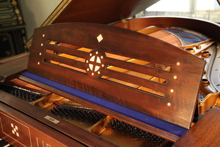 The music desk is in a simple design with cut-out slats, typical of Arts and Crafts. In the centre is an inlaid circle with central cross. Again when viewed as a Norse symbol, this suggests the sun wheel, one of the oldest spiritual symbols of the Germanic people. The central cross seperates the circle into four pieces, just like the seasons in a year. It is representative of life, fertility and peace.
