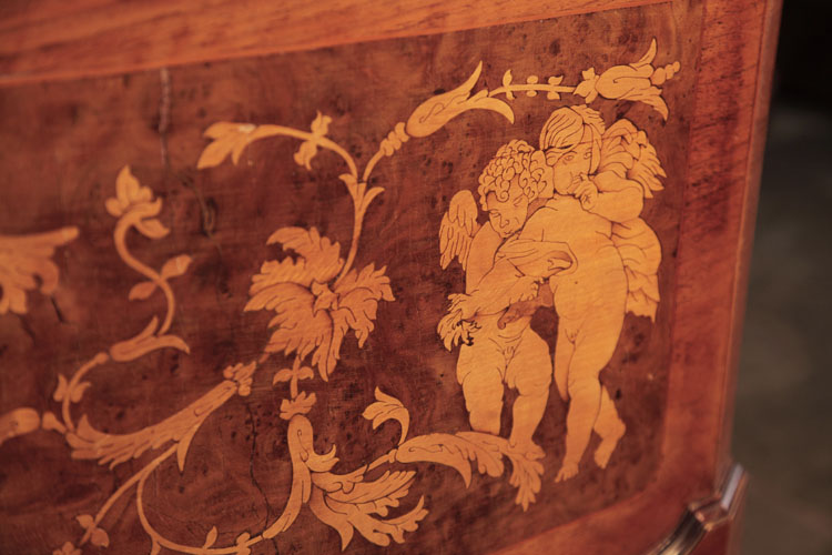 Detail of hugging, winged cherubs on piano cabinet 