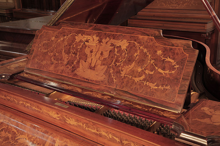 Lipp piano music desk inlaid with a central design of kneeling winged figures lifting a bowl filled with scrolling hibiscus flowers and foliage