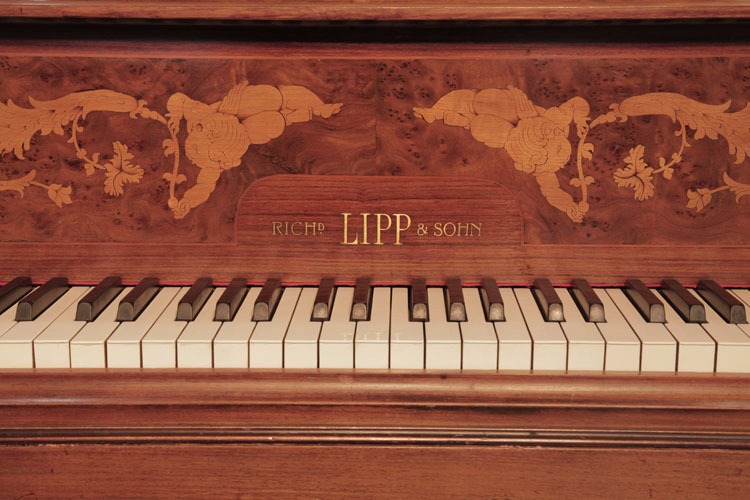 Lipp manufacturers name inlaid in brass on fall surrounded by inlay of reclining cherubs 