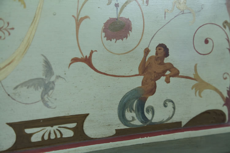 Hand-painted detail of a reclining male figure with birds and arabesques