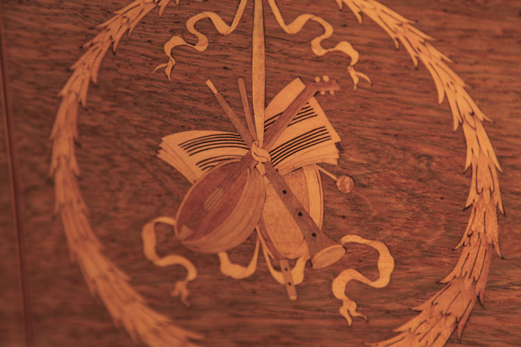 Inlay detail of music instuments suspended from a bowed wreath