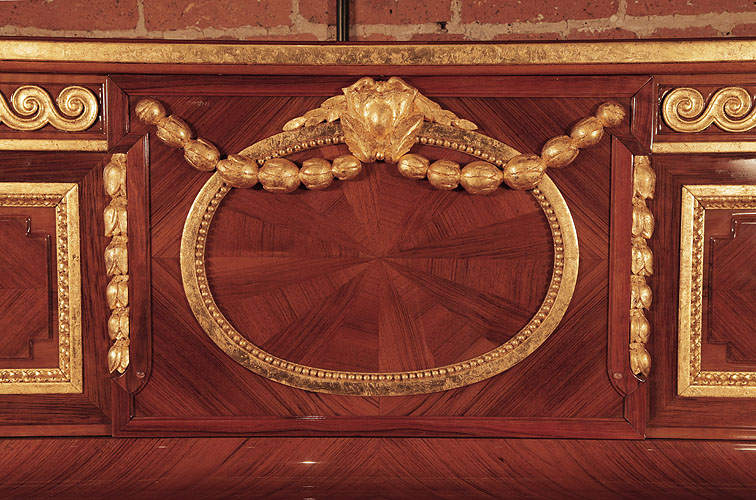 Steinway front panel inlaid with walnut in a sunburst design. Panel features a gold oval with a beading surround, draped with swagged bellflowers and a central cartouche.