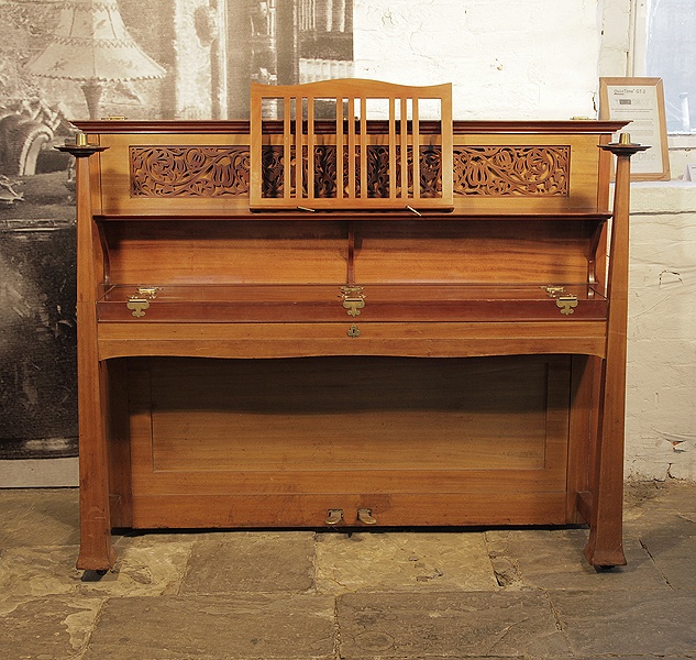 An 1898, Arts and Crafts style, Bechstein upright piano with a walnut case and ornate fretwork panel cut in a sinuous floral design